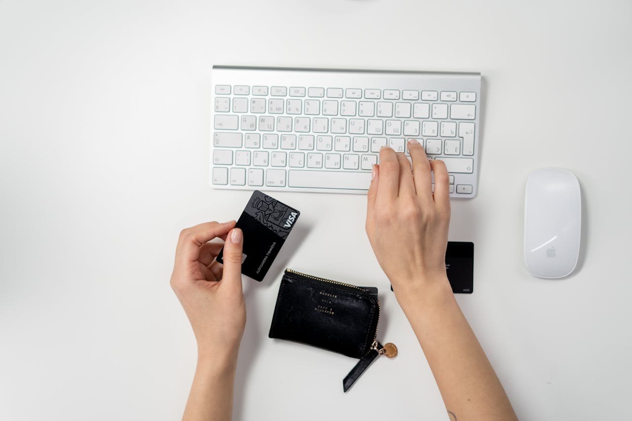 a person's hands holding a credit card and typing on a keyboard